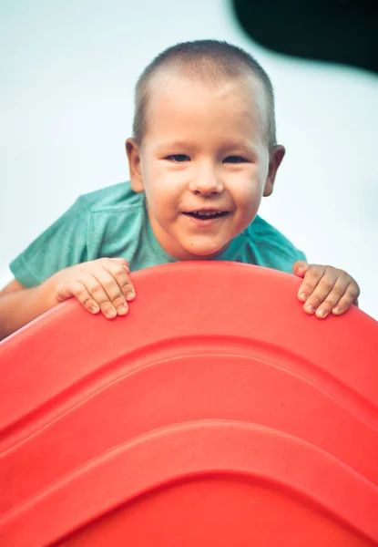 Piccolo ragazzo sorridente su uno scivolo — Foto Stock