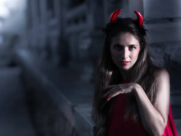 Hermosa mujer en vestido rojo y cuernos. Halloween — Foto de Stock