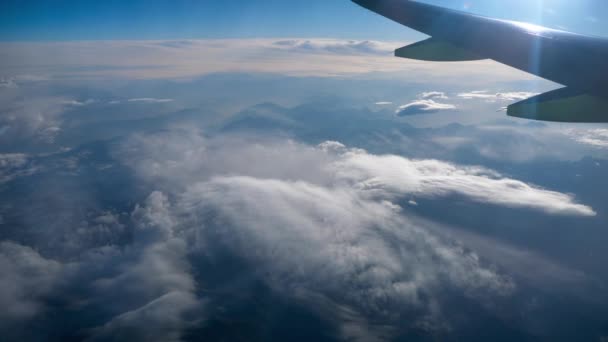 Hermosa vista a través de la ventana del avión, avión volando por encima de las montañas y nubes — Vídeo de stock