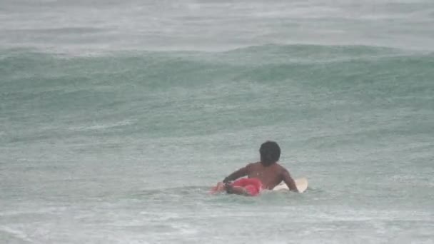 Surfista en las olas bajo la lluvia. — Vídeos de Stock