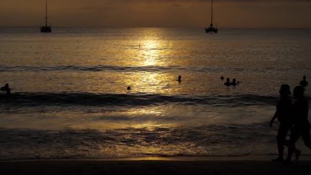 Закат с силуэтами людей наслаждается океаном . — стоковое видео