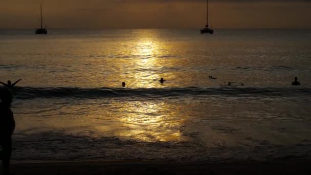 Beau coucher de soleil avec des silhouettes de personnes profiter de l'océan . — Video
