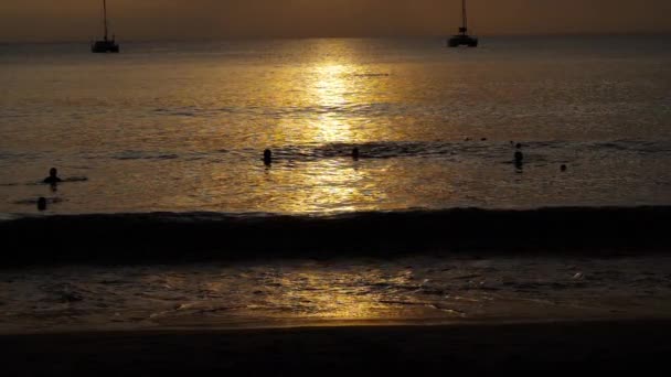 Beau coucher de soleil avec des silhouettes de personnes profiter de l'océan . — Video