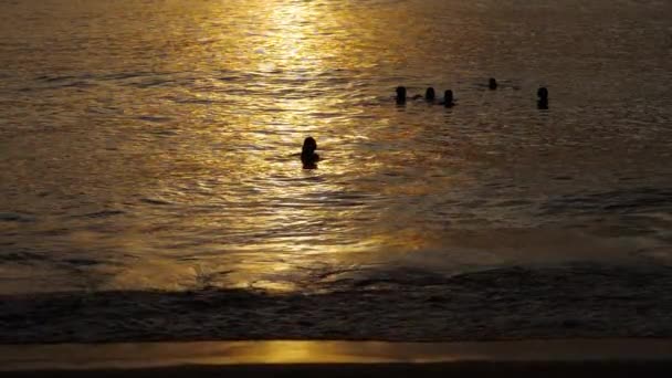 Υπέροχο ηλιοβασίλεμα με σιλουέτες των ανθρώπων απολαμβάνουν τον ωκεανό. — Αρχείο Βίντεο
