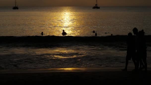 Υπέροχο ηλιοβασίλεμα με σιλουέτες των ανθρώπων απολαμβάνουν τον ωκεανό. — Αρχείο Βίντεο