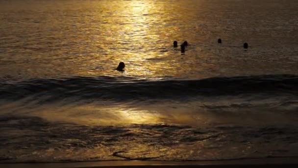 Beau coucher de soleil avec des silhouettes de personnes profiter de l'océan . — Video