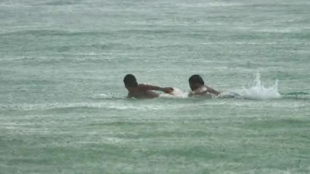 Surfista en las olas bajo la lluvia. — Vídeos de Stock