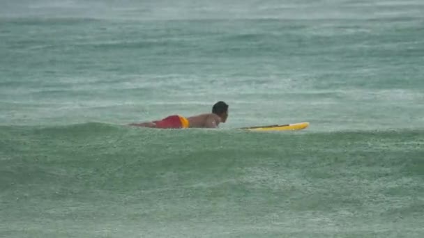 Surfista en las olas bajo la lluvia. — Vídeo de stock