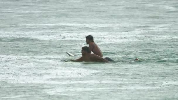 Surfista en las olas bajo la lluvia. — Vídeo de stock