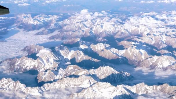 Beautiful view through airplane window, airplane flying above mountains with clouds — Stock Video