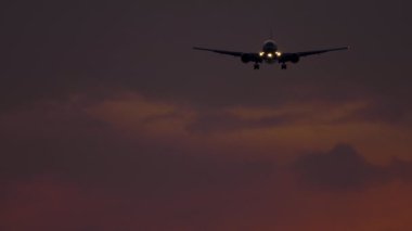 Gün batımında okyanus üzerinden yaklaşan uçak.