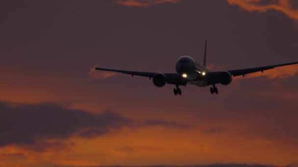 Vliegtuig nadert boven oceaan bij zonsondergang backgfround — Stockvideo