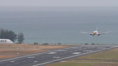 PHUKET, THAILAND - 25 Şubat 2025: Nok Air Boeing 737 HS-DBQ inişi, Phuket Havaalanı 'na iniş ve frenleme. Kalkıştan önce Finnair Airbus A350. Seyahat kavramı
