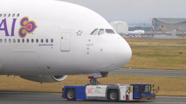 FRANKFURT AM MAIN, ALMANY - 20 Temmuz 2017: Frankfurt Havaalanı 'ndaki Tay Havayolları' nın geniş gövdeli Airbus A380 uçağını çeken römork. Uçağa yakın çekim. Seyahat kavramı