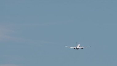 Açık mavi gökyüzüne yükselen ticari bir yolcu uçağının arka görüntüsü. Uçak kalkıştan sonra tırmanıyor, seyahat, havacılık ve özgürlüğün sembolü. Ulaşım, uçuş kavramları