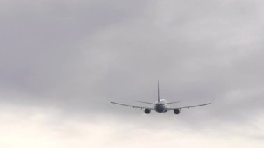 Kalkıştan sonra bulutlu gökyüzüne tırmanan ticari bir uçağın arka görüntüsü. Havacılık, seyahat ve özgürlüğün sembolik görüntüsü