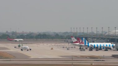 BANGKOK, THAILAND - 15 Mart 2025: Airplane Spring Airlines Airbus A320, B-6863 Suvarnabhumi Havaalanı 'nda taksicilik. Terminalde sıra sıra bekleyen uçaklar. Arka planda başka bir uçak kalkıyor..