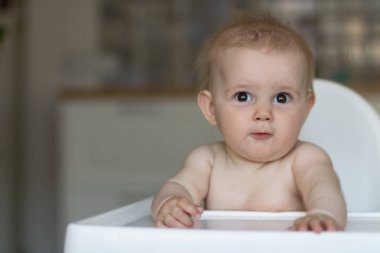 Küçük bir çocuk çocuk koltuğu mutfakta oturuyor. Kopya alanı