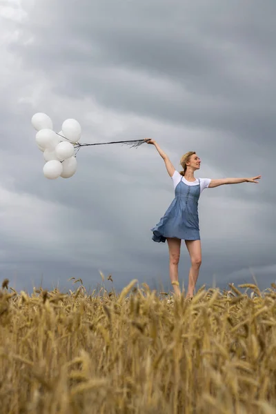 Šťastná žena s míčky v poli na obloze bouřka — Stock fotografie
