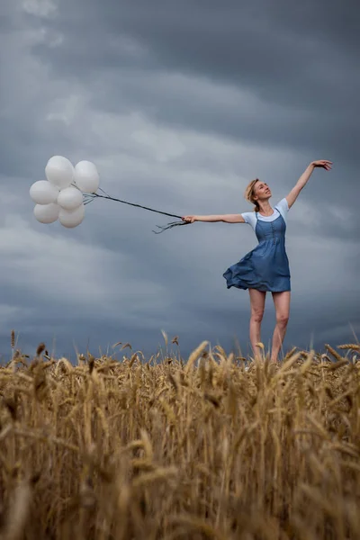 Šťastná žena s míčky v poli na obloze bouřka — Stock fotografie