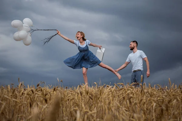 Hombre Reteniendo a la mujer volando con globos —  Fotos de Stock