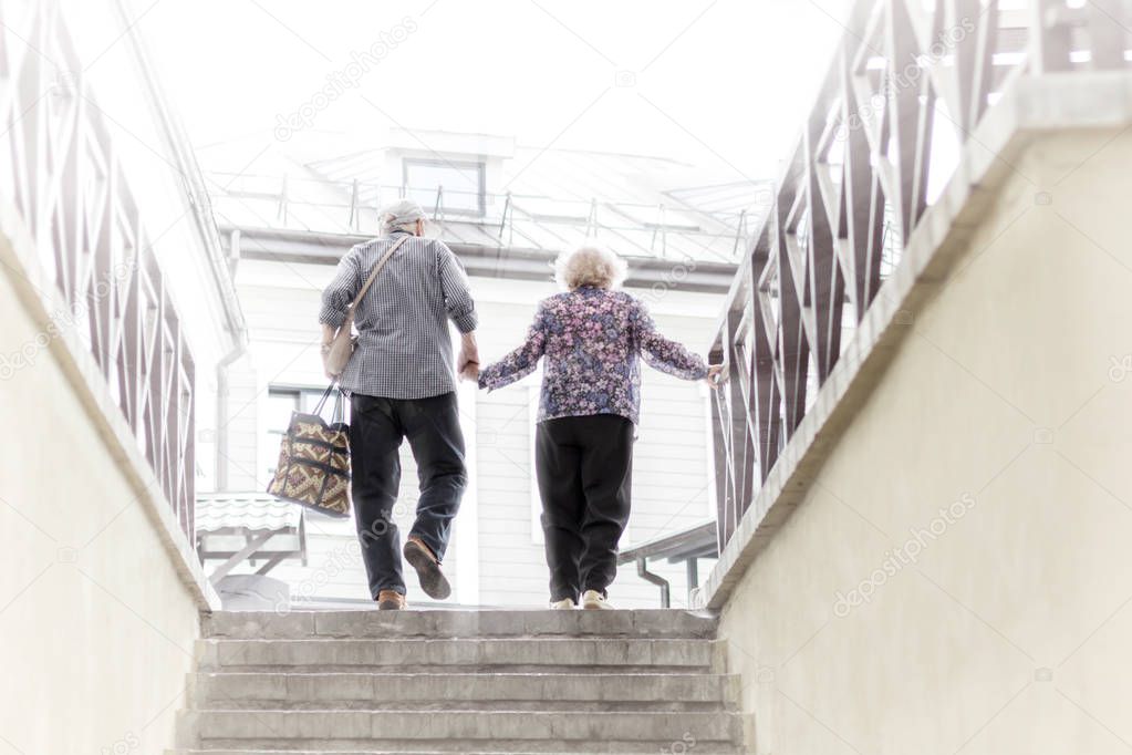 Old Man and Woman Holding Hands and Climbing the Stairs