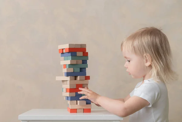 El niño preescolar construye una torre de bloques de madera. Desarrollo y Educación. Concepto para niños — Foto de Stock