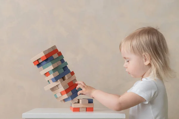 El niño preescolar construye una torre de bloques de madera. Desarrollo y Educación. Concepto para niños — Foto de Stock