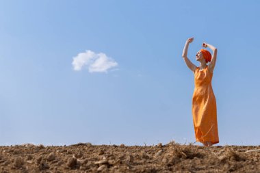 Türbanlı Etnik Kadın Gökyüzünde Temiz Toprakta Dans Ediyor ve Bulutlar Arka Planda