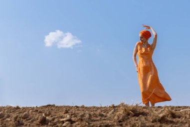 Türbanlı Etnik Kadın Gökyüzünde Temiz Toprakta Dans Ediyor ve Bulutlar Arka Planda