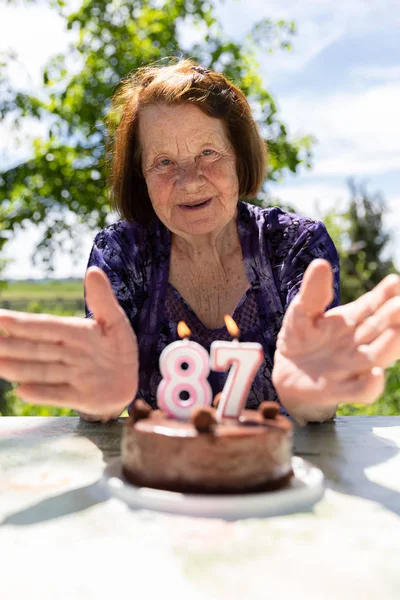 Merry Old Lady Blows Festive Candles on the Cake — Stock Photo, Image