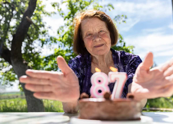 Merry Old Lady Blows Festive Candles on the Cake — Stock Photo, Image