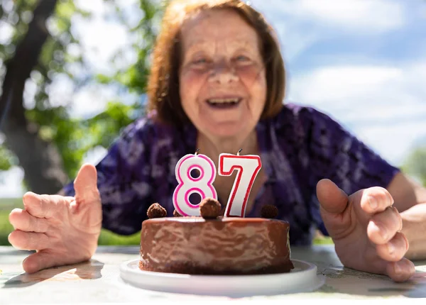 Весела стара леді дає святкові свічки на торт — стокове фото