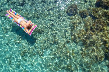 Denizde bir yatak üzerinde bikini güzel bir genç kadının havadan görünümü