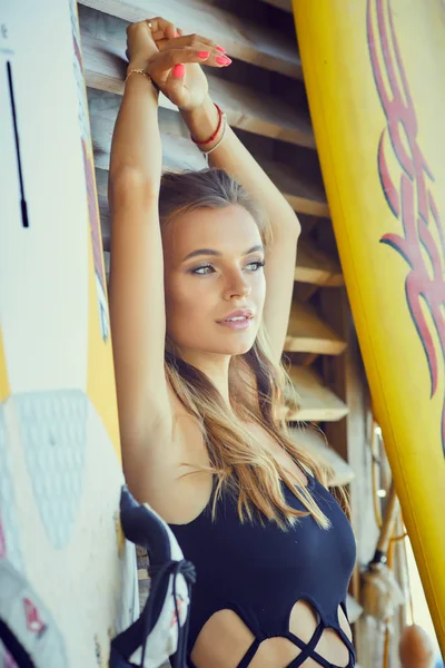 若いセクシーな女性長い毛と 陽気な日焼けボディ ビーチ サーフィンのための準備にサーフィン ボードを浮かべてします 手を振っています 肯定的な感情 — ストック写真