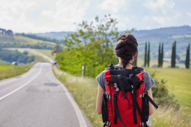 ülke yolda yürürken sırt çantası taşıyan güzel gezgin kadın.