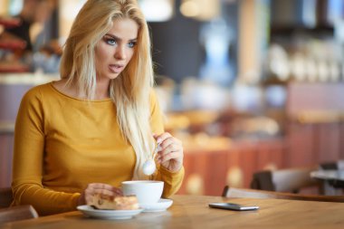 Gülümseyen çekici genç hanım çay yudumlarken pencereden bakıyor