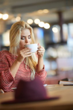 Gülümseyen çekici genç hanım çay yudumlarken pencereden bakıyor