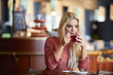 Gülümseyen çekici genç hanım çay yudumlarken pencereden bakıyor