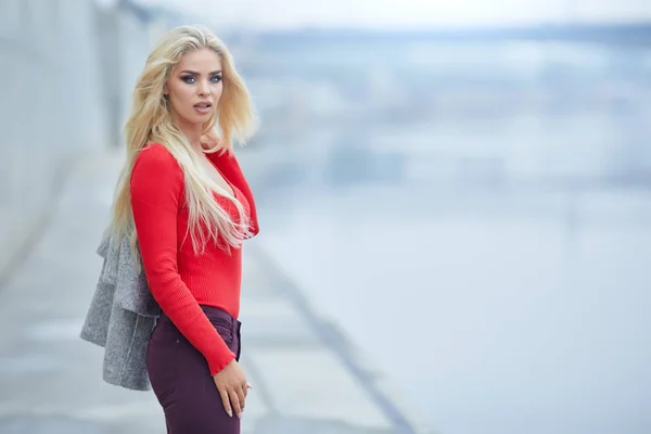 川の前に赤いセーター ポーズでゴージャスな女性 — ストック写真