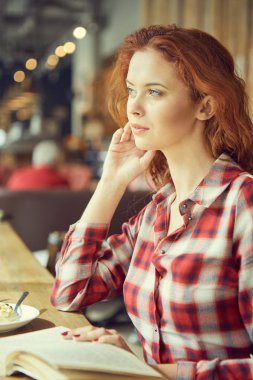 Kız kafede kahve içme ve bir kitap okuma