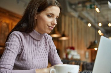 Güzel esmer kafede dizüstü bilgisayar kullanarak. Blogger iş kavramı