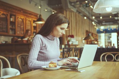 Güzel esmer kafede dizüstü bilgisayar kullanarak. Blogger iş kavramı