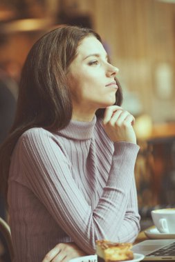 Güzel esmer kafede dizüstü bilgisayar kullanarak. Blogger iş kavramı