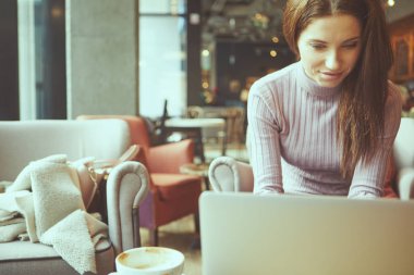Güzel esmer kafede dizüstü bilgisayar kullanarak. Blogger iş kavramı