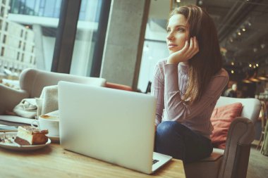 Güzel esmer kafede dizüstü bilgisayar kullanarak. Blogger iş kavramı