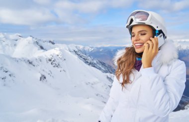 Bir dağ kayak merkezi çekici genç kadın. Cep telefonu sohbet ve gülen bir kar üzerinde duran         