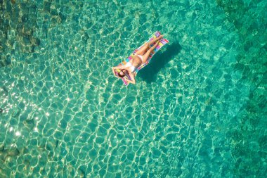 Yukarıdan aşağıya bir hava yatağı üzerinde yüzen bir güzel kadının beyaz bir bikini görünümü 