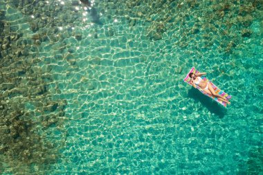 Yukarıdan aşağıya bir hava yatağı üzerinde yüzen bir güzel kadının beyaz bir bikini görünümü 