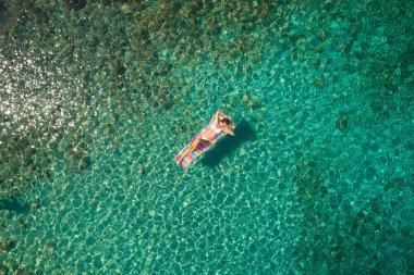 Yukarıdan aşağıya bir hava yatağı üzerinde yüzen bir güzel kadının beyaz bir bikini görünümü 